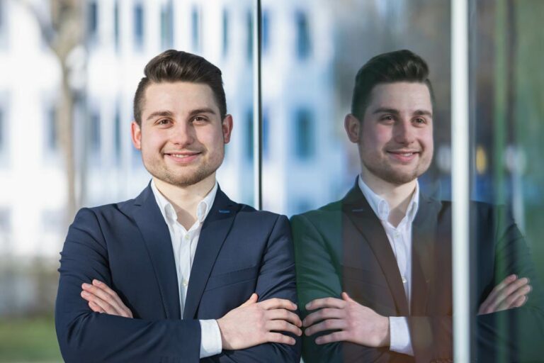 Bewerbungsfotos in Dresden - ein junger Mann lehnt sich an einem Fenster spiegelt und in die Kamera schaut