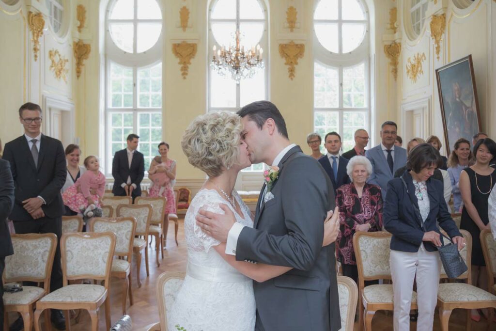 Hochzeitspaar küsst sich während der standesamtlichen Hochzeit auf Schloss Oberlichtenau