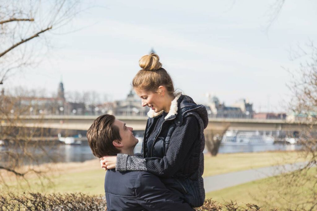 Fotoshooting natürliche Paar Fotogafie in Dresden - Freund hebt seine Freundin hoch und beide schauen sich verliebt an
