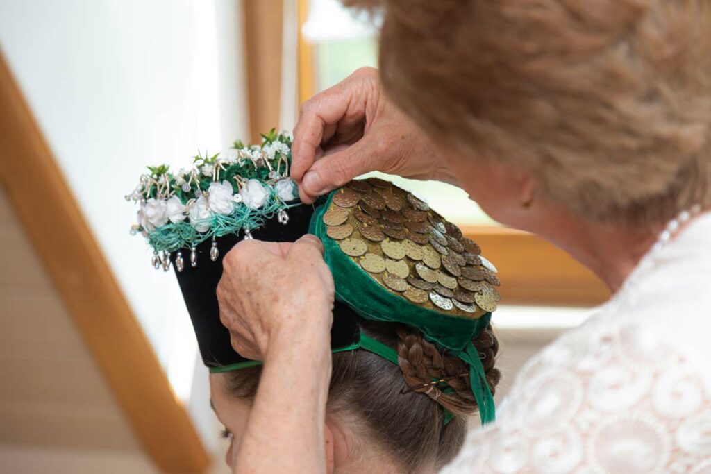 Die sorbische Braut wird für ihren großen Tag fertig gemacht. Der Haarschmuck wird gerade befestigt.