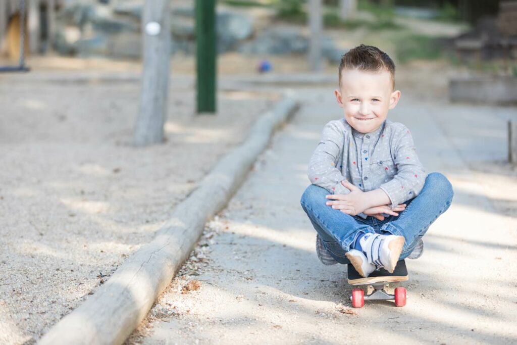 ein junge sitzt auf dem skatboard und lächelt dabei in die kamera des fotografen in dresden. Bilder für die Erinnerungen einer Familie.