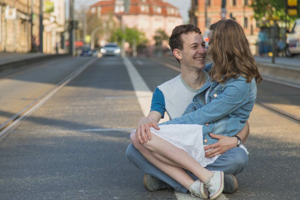 Engagement Shooting in Dresden - Paar sitzt auf einer Straße und schauen glücklich und genießen die Zeit