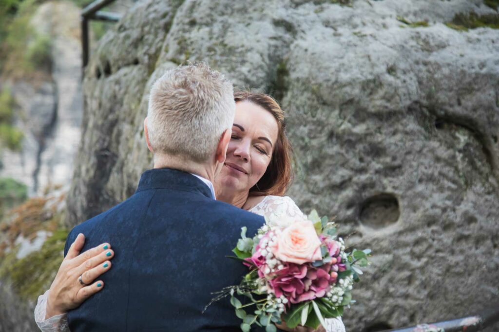 Brautpaar stehen eng beieinander und genießen ihren Hochzeitstag in der sächsischen schweiz auf der Bastei