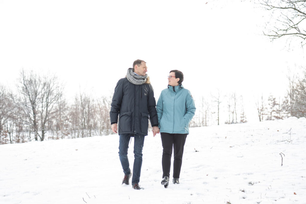 ein Paar läuft im Schnee eng beieinander und sie genießen die Zeit. wunderschöne Paarfotos nicht im Studio, sondern Outdoor. Ein tolles Winter-Fotoshooting in Dresden und Umgebung mit Jan Windisch Fotografie.