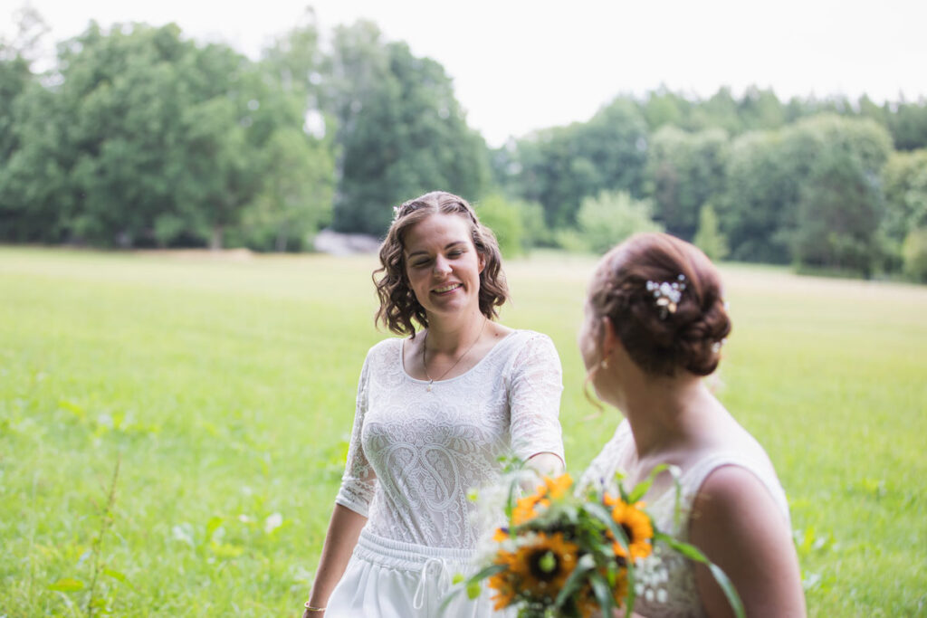 zwei Frauen schauen sich verliebt an und laufen auf einer Wiese. Brautpaarshooting in Meißen