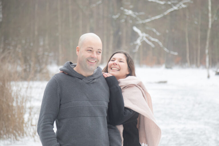 eine Frau schaut ihren Mann freudestrahlend an den sie liebt. Ein klassisches Winter Fotoshooting in Dresden mit einem tollen verliebten Paar.