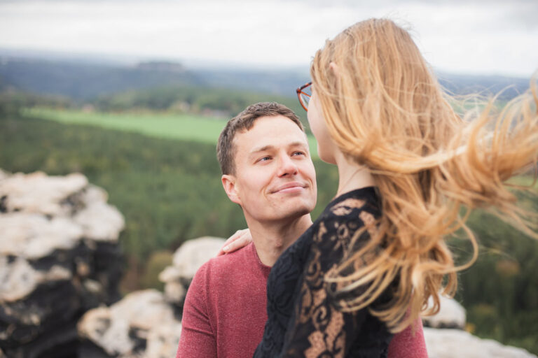 Fotoshooting in der Nähe von Dresden mit einem jungen Paar. Beide schauen sich verliebt an und sitzen eng beieinander.