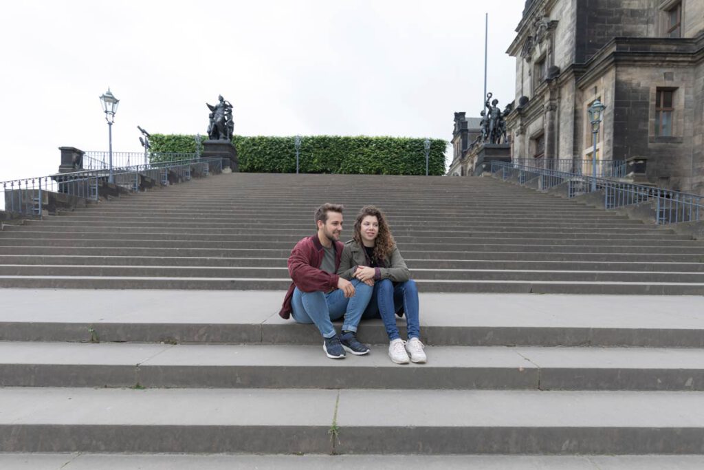 ein junges Paar sitzt auf einer Treppe in Dresden. Tolle Bilder die die Liebe eines Paares außerhalb des Studios aufgenommen wurden, sozusagen ein natürliches und authentisches Fotoshooting in Dresden.