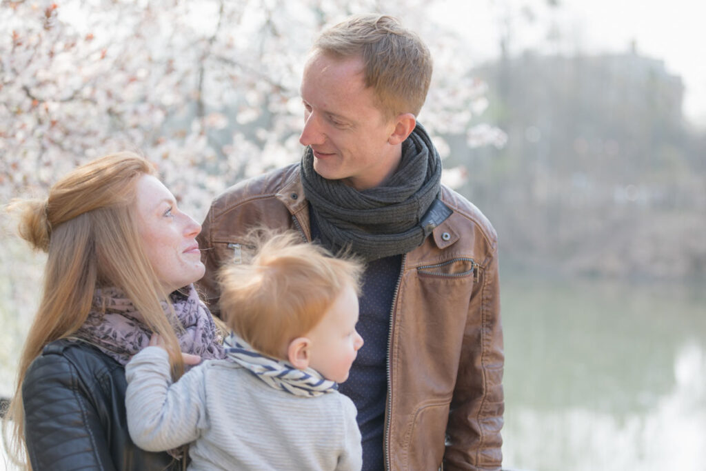 Familienfoto im Grünen - die Familie interagiert miteinander und sie schauen nicht zum Fotografen. Ein sehr schönes natürliches Bild der Familie.