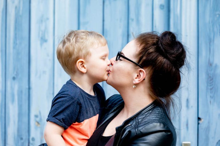 Eine Mama hat ihren Jungen auf dem Arm und geben sich einen Kuss