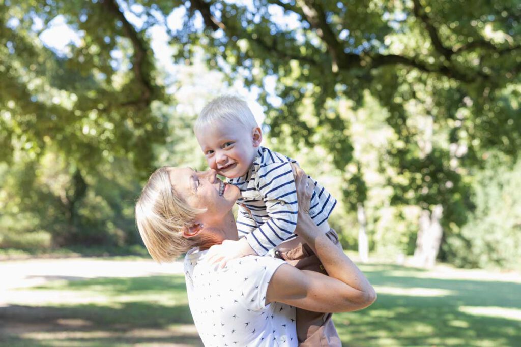 Mama hebt ihren Jungen hoch und sie haben Spaß mit einander