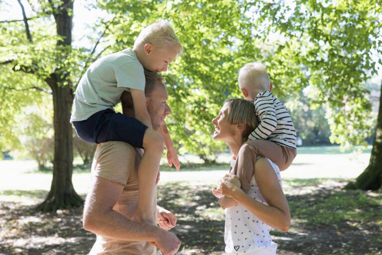 Kinder sitzen auf den Schultern der Eltern
