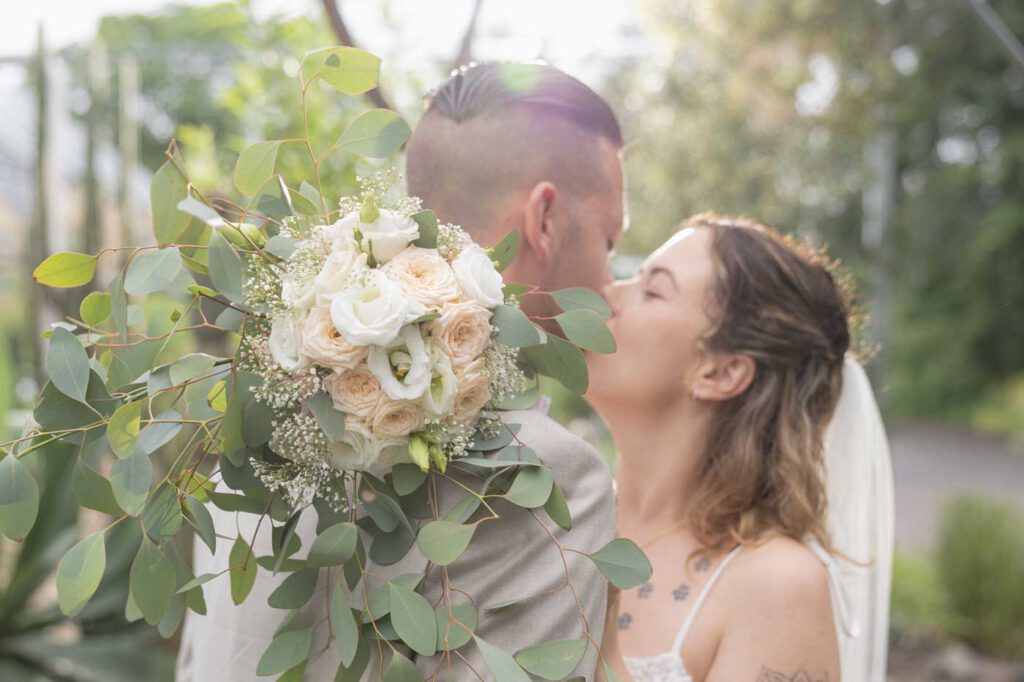 Brautpaar küsst sich während es draußen regnet zur Regen Sommerhochzeit Dresden im Botanischen Garten