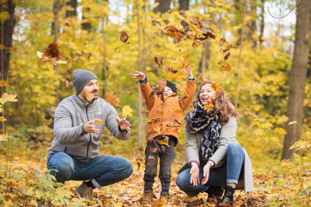 Familien Fotoshooting im Herbst - Familie werfen Blätter hoch und schauen danach