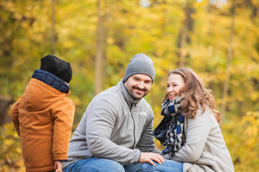 Mama und Papa sind engbeieinander und ihr Kind läuft auf sie zu