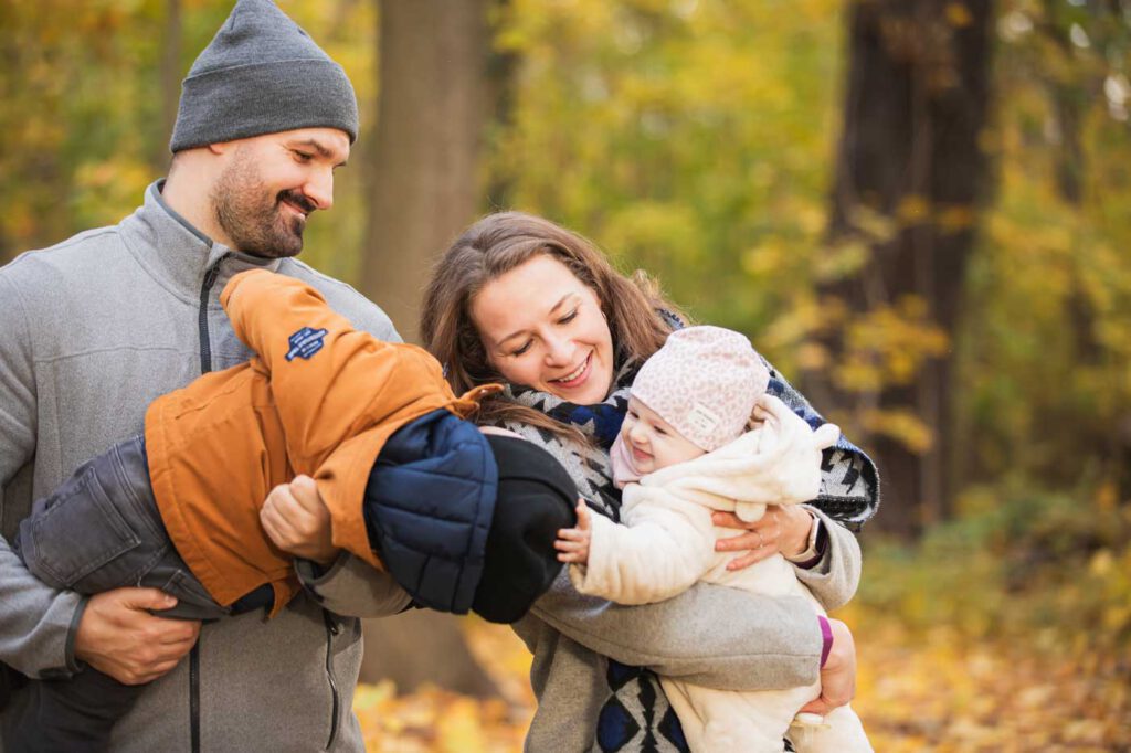 Kinder sind auf den Arm von den Eltern und interagieren mit einander - Herbst Fotoshooting