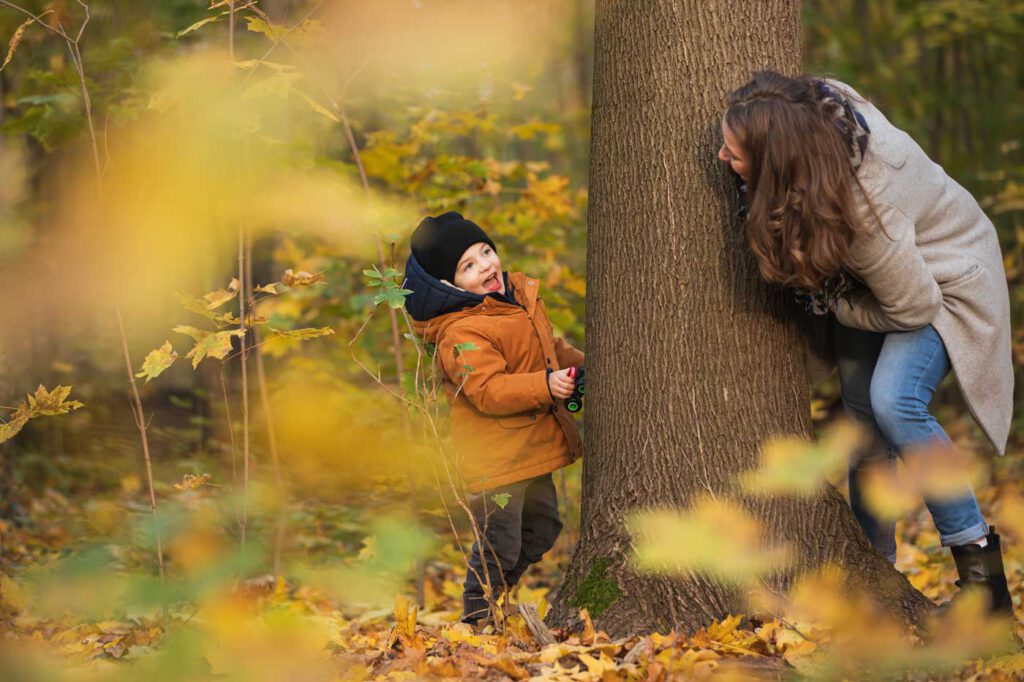 Versteckspielen hinter einem Baum von Sohn und Mama - Laubfärbung - Herbst Fotoshooting
